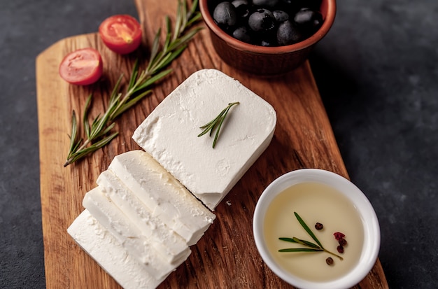 queso feta, con romero, tomates, aceitunas sobre un fondo de piedra.