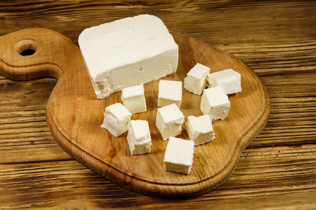 Queso feta en tabla de cortar sobre una mesa de madera