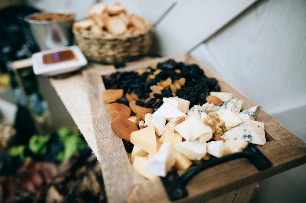 Queso frutos secos y nueces sobre una tabla de madera en un restaurante en la mesa de bodas Servicio de catering