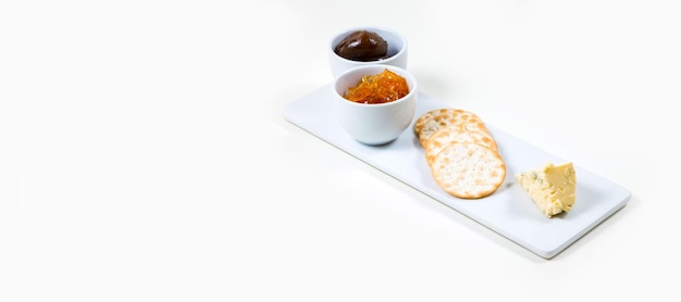 Queso y galletas en un plato blanco sobre un fondo blanco aislado