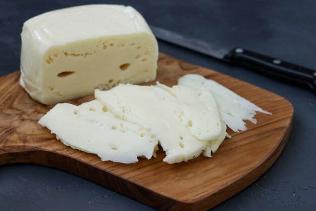 Queso georgiano Suluguni en rodajas sobre una tabla de madera