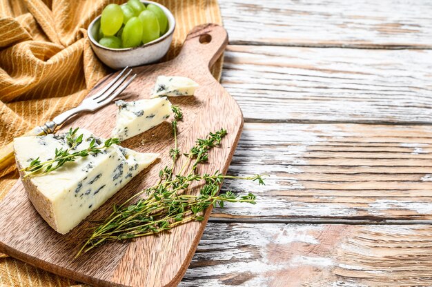 Queso Gorgonzola francés con uvas. Fondo de madera blanca. Vista superior. Copie el espacio.