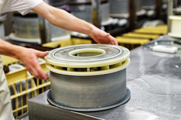 Queso Gruyere de Comte prensado en las formas especiales en la lechería en Franche Comte, Borgoña, Francia. Como parte del proceso de producción.