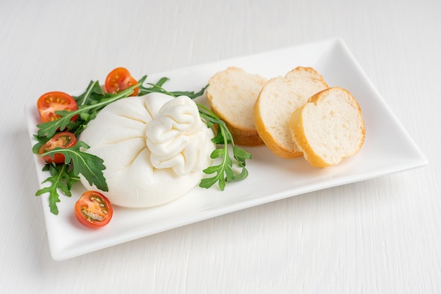 Foto queso de leche italiano burrata orgánico suave casero hecho de crema servido con rúcula y tomates