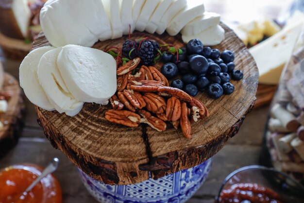 Foto queso en lonchas y trozos con nueces y arándanos