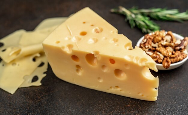 Queso maasdam con nueces y romero en mesa de piedra