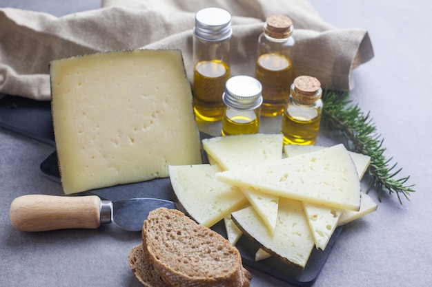 Foto queso manchego curado y aceite de oliva en una tabla para cortar