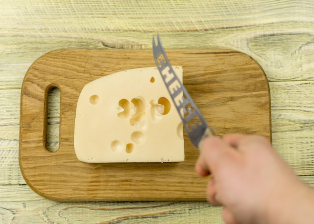 Foto queso y mano con un cuchillo para cortar queso