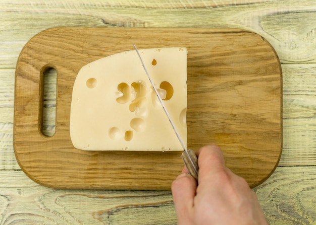 Foto queso y mano con un cuchillo para cortar queso