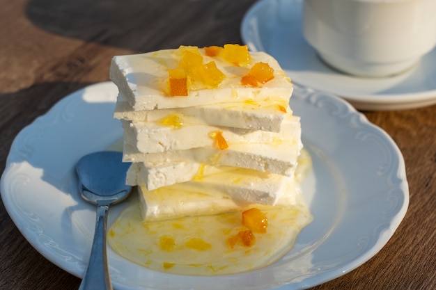 Queso con mermelada de limón y taza de café sobre la mesa