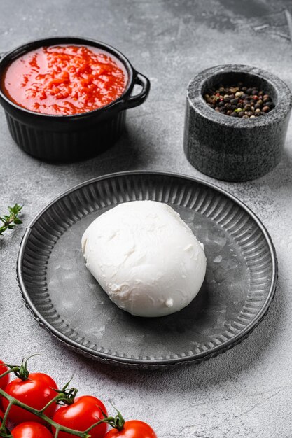 Queso mozzarella, albahaca y tomate, sobre fondo de mesa de piedra gris