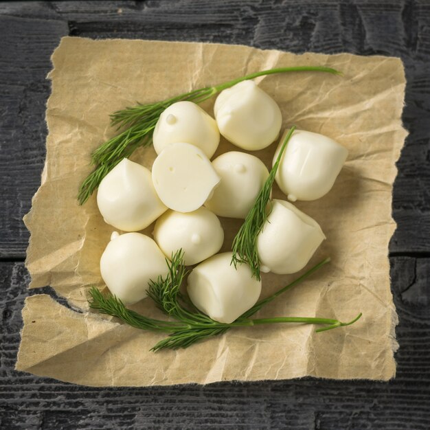 Queso mozzarella recién hecho con eneldo sobre una mesa de madera