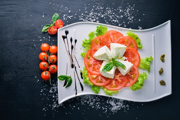 Queso mozzarella con tomate y aceite de oliva Comida italiana Sobre un fondo de madera Vista superior Espacio libre para texto