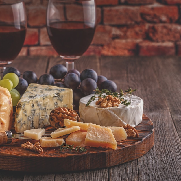 Foto queso, nueces, uvas y vino tinto sobre fondo de madera