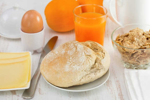 Queso, pan, cereales, huevo y zumo sobre la mesa.