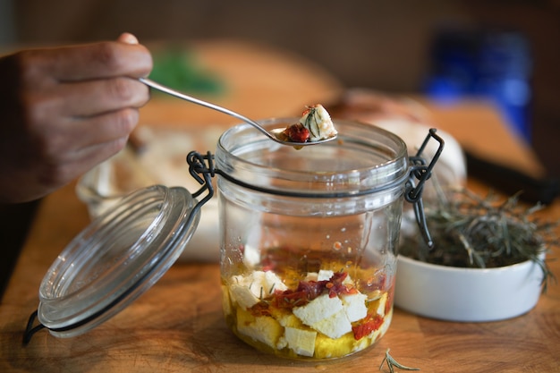 Queso paneer campesino, tomates secos y romero marinado en aceite de oliva en tarro de cristal. comida vegetariana