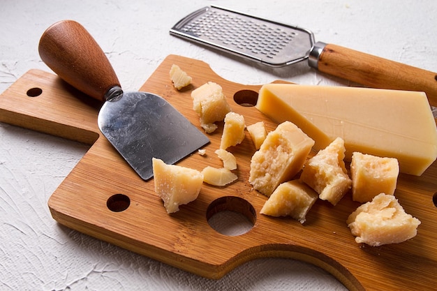 Foto queso parmesano duro en una tabla de cortar queso cuchillo rallador vista superior sin gente