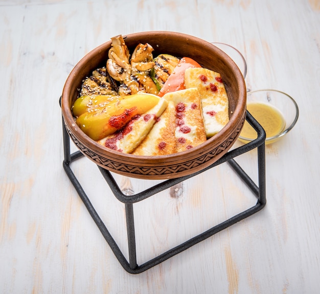 Queso a la plancha con verduras a la plancha en un plato de arcilla