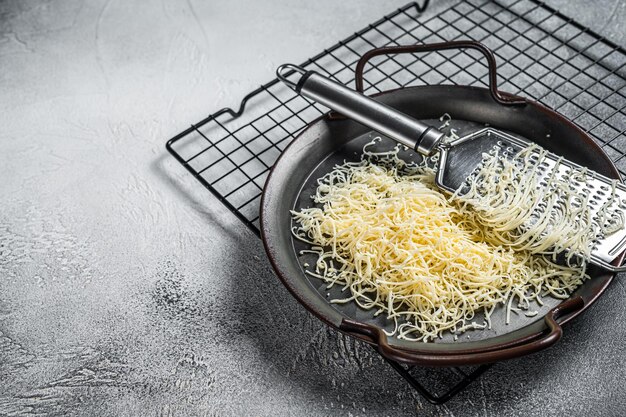 Queso rallado para cocinar en una bandeja de acero con rallador Fondo blanco Vista superior espacio de copia