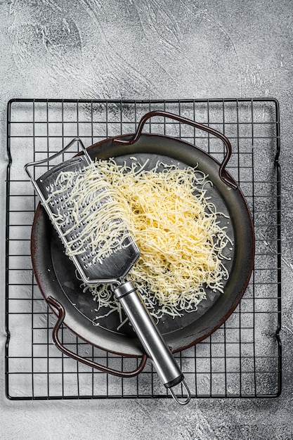 Queso rallado para cocinar en una bandeja de acero con rallador Fondo blanco Vista superior