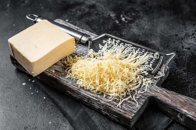 Queso rallado para cocinar en una tabla de cortar Fondo negro Vista superior