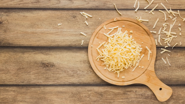 Foto queso rallado en tabla de cortar sobre el escritorio