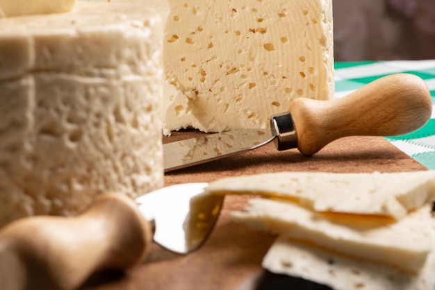 Queso semicurado de Brasil dispuesto en una tabla rústica sobre un mantel a cuadros verde y blanco, enfoque selectivo.