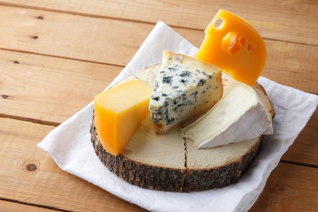 Queso sobre tela blanca. Camembert, queso amarillo duro, dorblu sobre tablas de madera. Productos lácteos en servilleta blanca