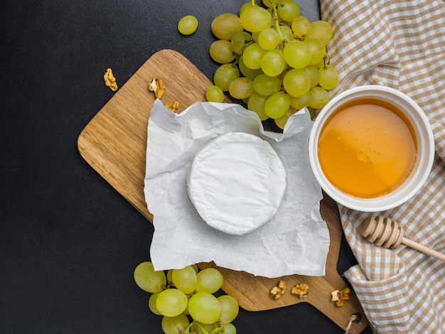 Queso suave. Camembert, miel y uvas en una madera con nueces.