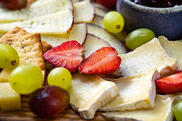 Queso surtido con frutas y mermelada sobre una tabla de madera. sirviendo la mesa y bocadillos al vino para el banquete.