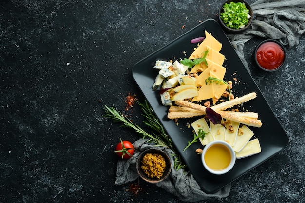 Queso surtido con miel en un plato negro Vista superior Espacio libre para su texto