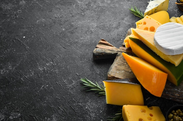 Queso Surtido de quesos y bocadillos sobre fondo de piedra negra Vista superior Espacio libre para su texto