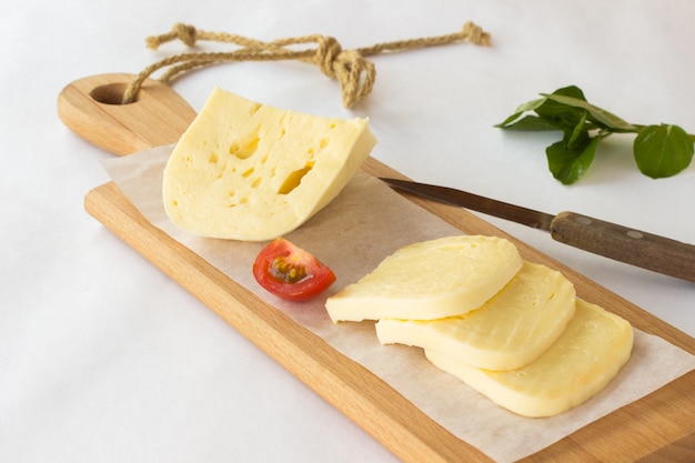 Queso, tomate y albahaca verde sobre una tabla para cortar.