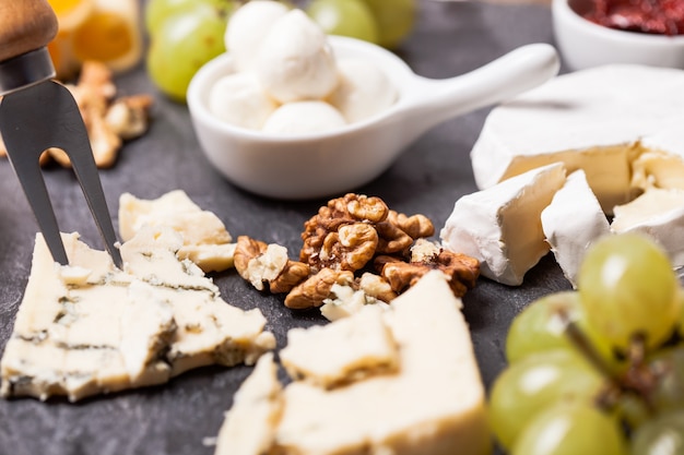 Queso y uva y nueces sobre una placa de pizarra