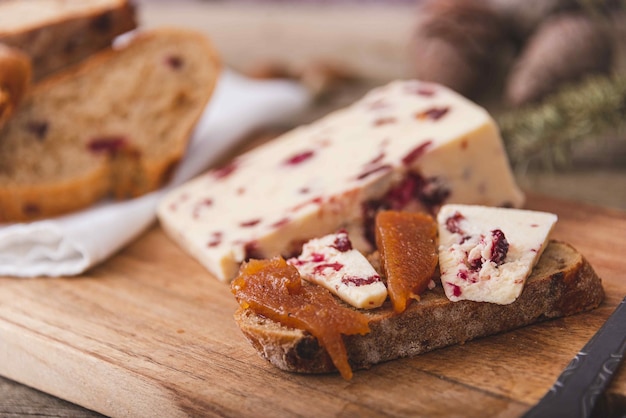 Queso Wensleydale con arándanos, vino tinto, miel, nueces, pasas sobre tabla de cortar de mármol, fondo de hormigón negro, enfoque selectivo