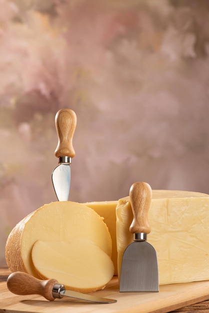 Foto quesos hermosos pedazos de queso y accesorios colocados en madera rústica fondo claro enfoque selectivo