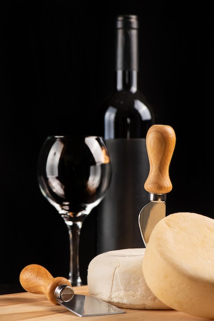 Foto quesos y vino una hermosa composición con quesos y vino y accesorios en madera con un fondo oscuro enfoque selectivo