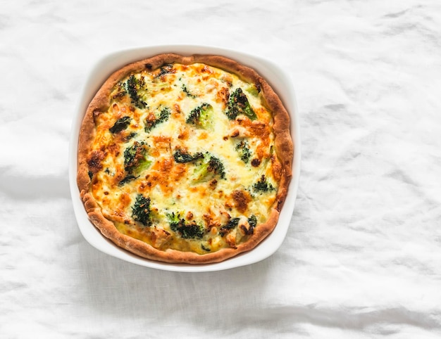 Quiche com brócolis, frango, espinafre e queijo em um fundo claro, vista de cima