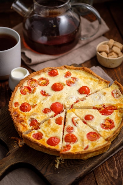 Foto quiche de torta cremosa com tomate cereja e frango na aldeia em uma mesa de madeira