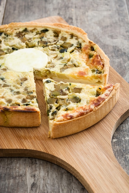 Foto quiche francesa lorena com legumes em uma mesa de madeira rústica