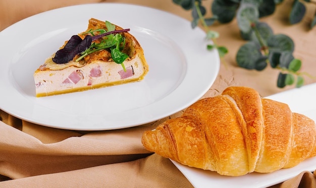 Quiche Lorraine y croissant en platos blancos