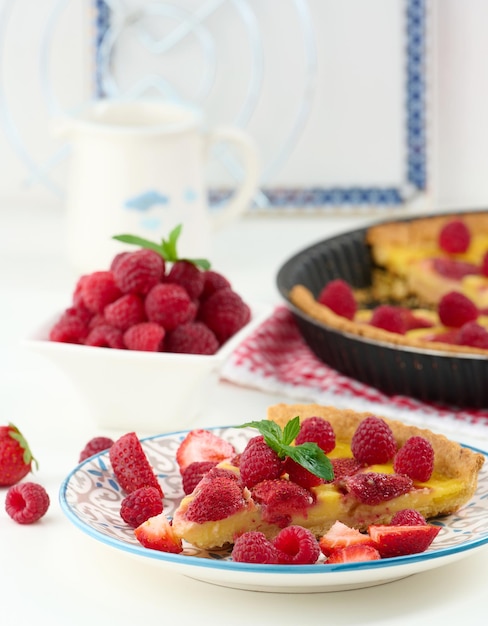 Quiche redondo con fresas rojas y frambuesas sobre una mesa blanca