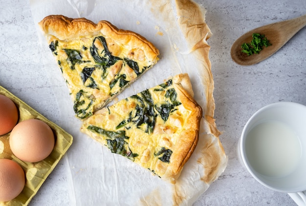 Quiche Scheiben gefüllt mit Huhn, Mangold mit Holzlöffel auf weichem Tisch