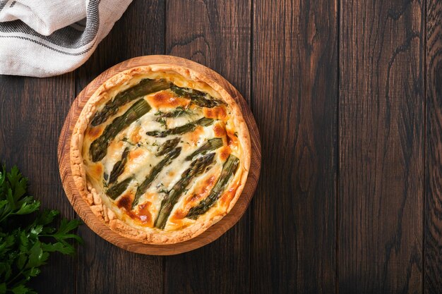 Quiche Selbst gemachter Spargelkuchen oder Quiche mit Käse und Spinat auf altem dunklem Holztischhintergrund Draufsicht