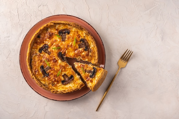 Quiche de tarta tradicional francesa con champiñones y queso con un trozo cortado en un plato