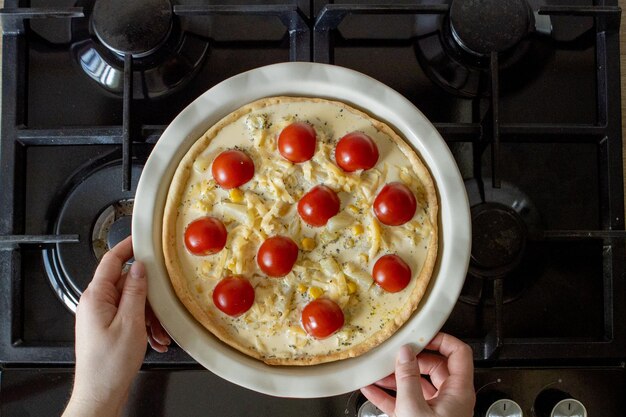 Quiche wird von einer Frau mit Ofenhandschuhen aus dem Ofen genommen