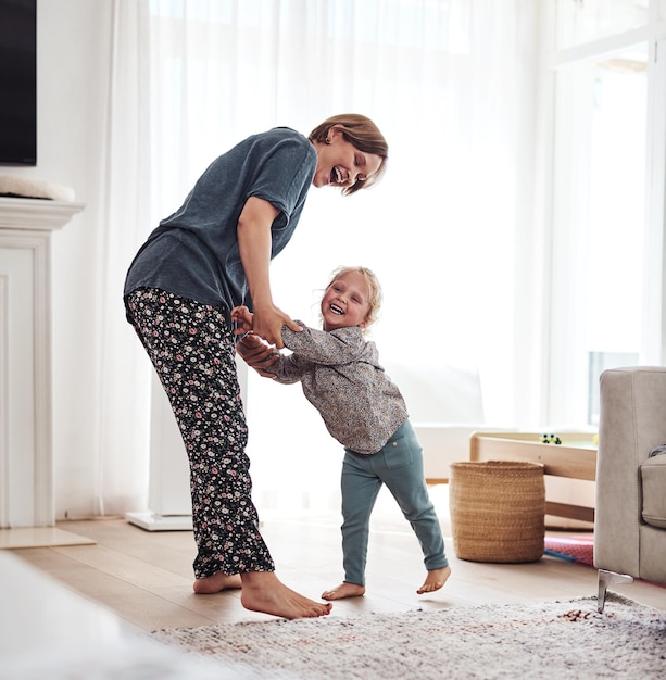 Quiero bailar con mi mamá Toma completa de una madre joven y atractiva jugando con su hija en la sala de estar en casa