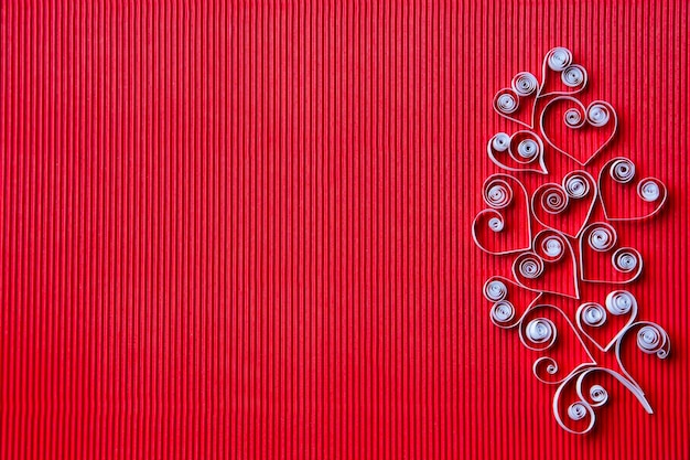 Quilling papel sobre cartolina vermelha. Fundo com corações para o dia dos namorados.