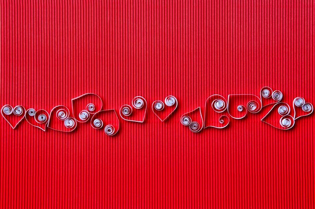 Quilling-Papier auf weißem Karton. Hintergrund mit Herz zum Valentinstag.