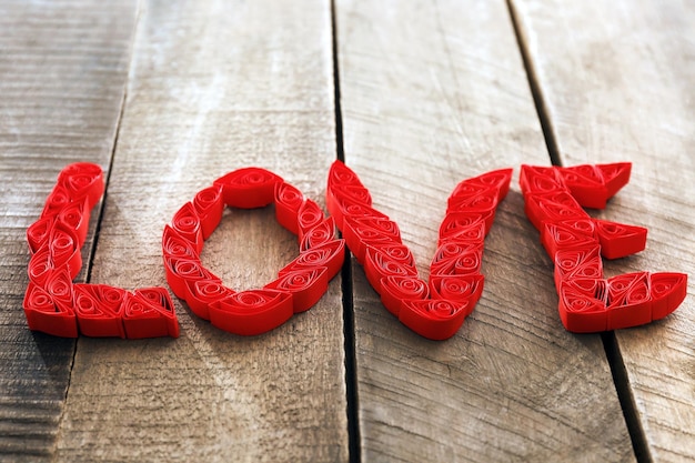 Quilling rojo palabra amor sobre fondo de madera